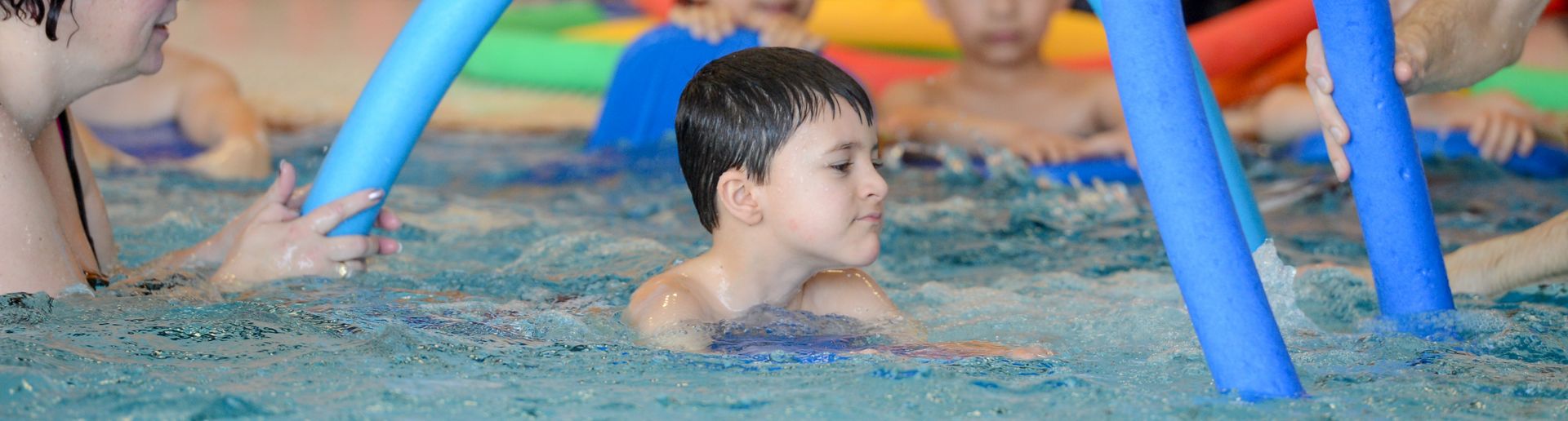Kind schwimmt durch Nudel-Bogen