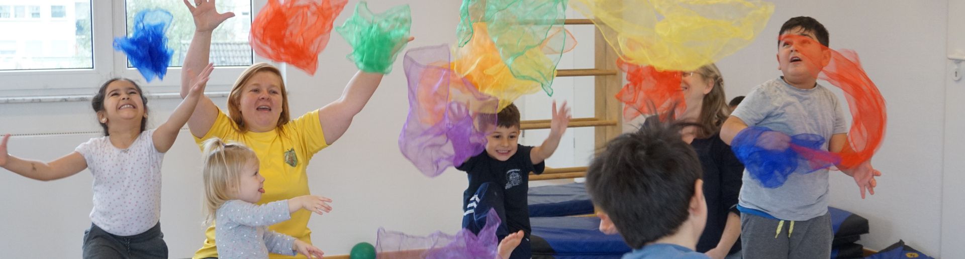 Kinder wedeln mit Übungsleiterin mit bunten Tüchern