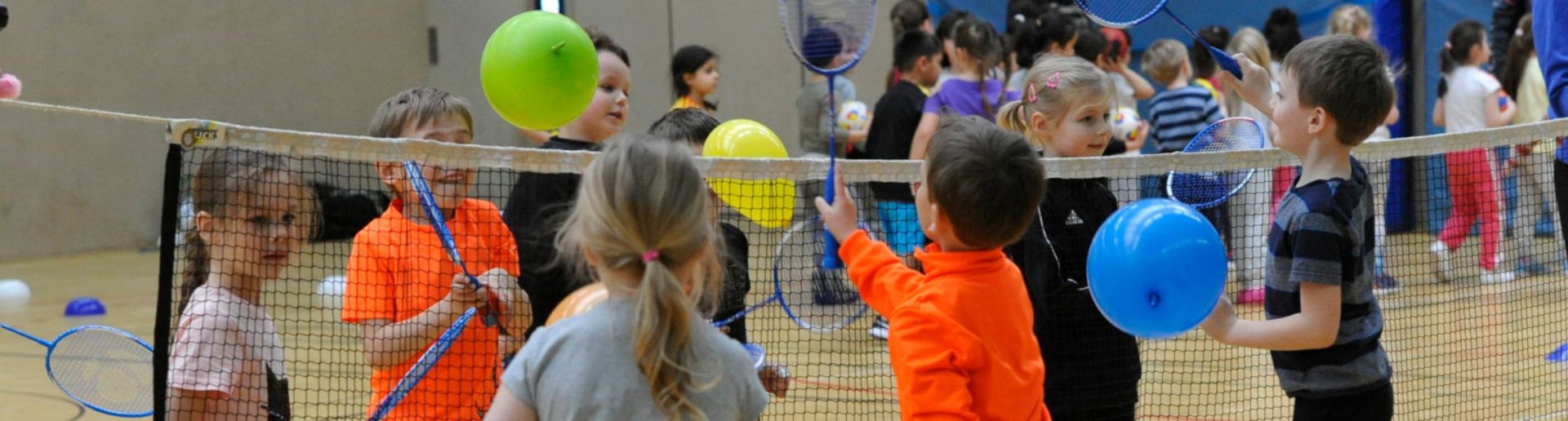 Kinder spielen mit Luftballons Badminton
